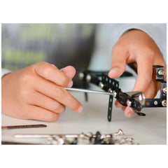 Child assembling Alexander Constructor Lorry Truck with a screwdriver, connecting black metal pieces on a white table.