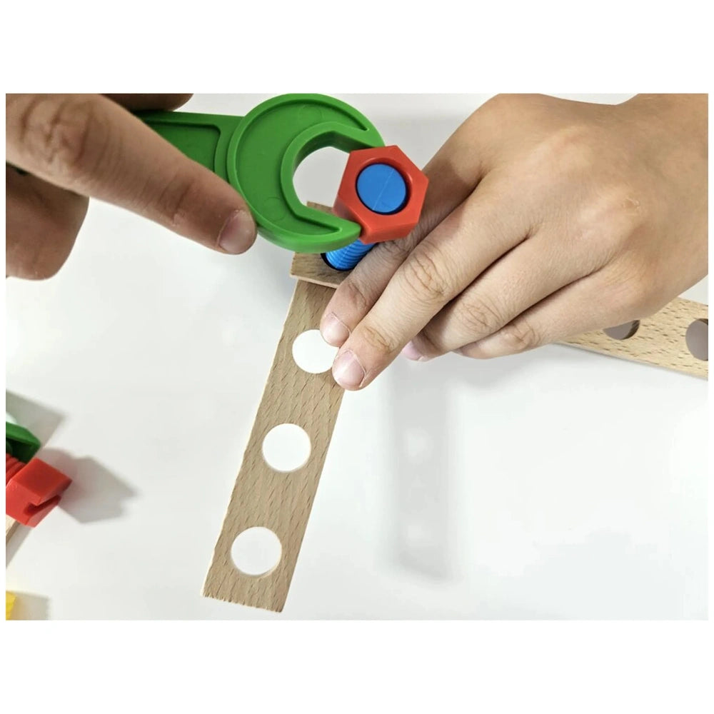 Child assembling race car with green wrench, colorful screw, and wooden board from Alexander Maly Constructor set.