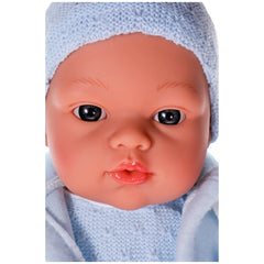 Lifelike Koke doll with blue eyes and knitted blue hat, showcasing realistic features and rosy cheeks.