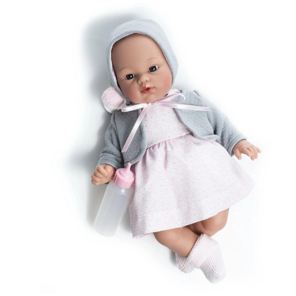 Asi Dolls Koke wearing a pink dress and gray jacket, holding a pink bottle, with striking blue eyes and lifelike features.