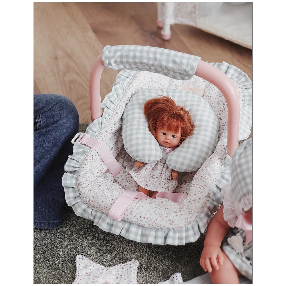 Doll in a gingham Maxi-Cosi with neck cushion, soft pink handle, floral ruffles; part of Asi Dolls Cloe Collection.