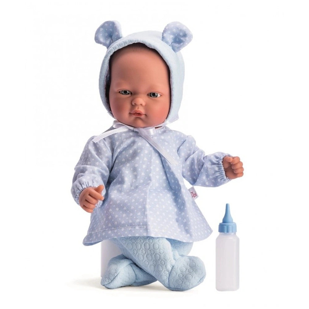 Lifelike baby doll in blue polka dot outfit and bonnet, sitting with bottle beside.