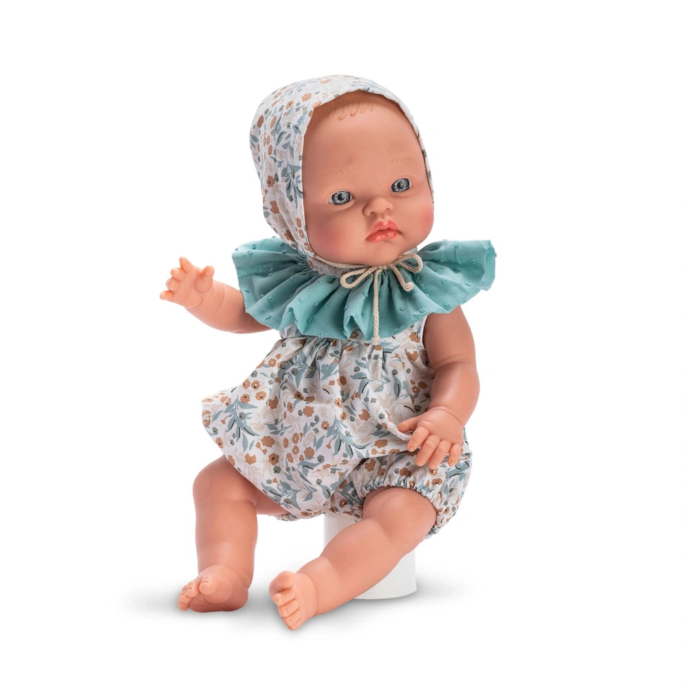 Doll wearing aqua hooded outfit with floral design, seated with lifelike expression and clear eyes, meant for interactive play.