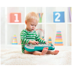 Baby Clementoni toy keyboard in a child's hands, featuring bright colors, as the child sits on a white carpet.