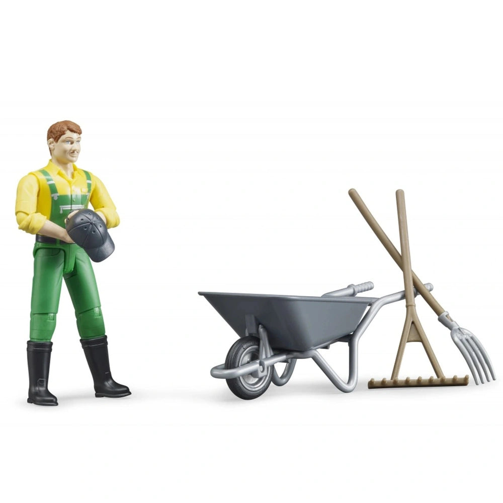 Farmer figure in green overalls with a wheelbarrow, pitchfork, and besom set for imaginative farm play.