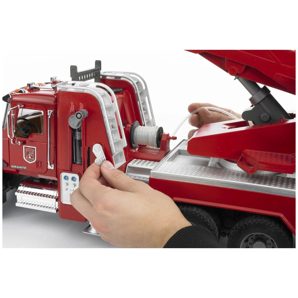 Hands interacting with the red Bruder MACK Granite Fire Engine's water pump and hose components.