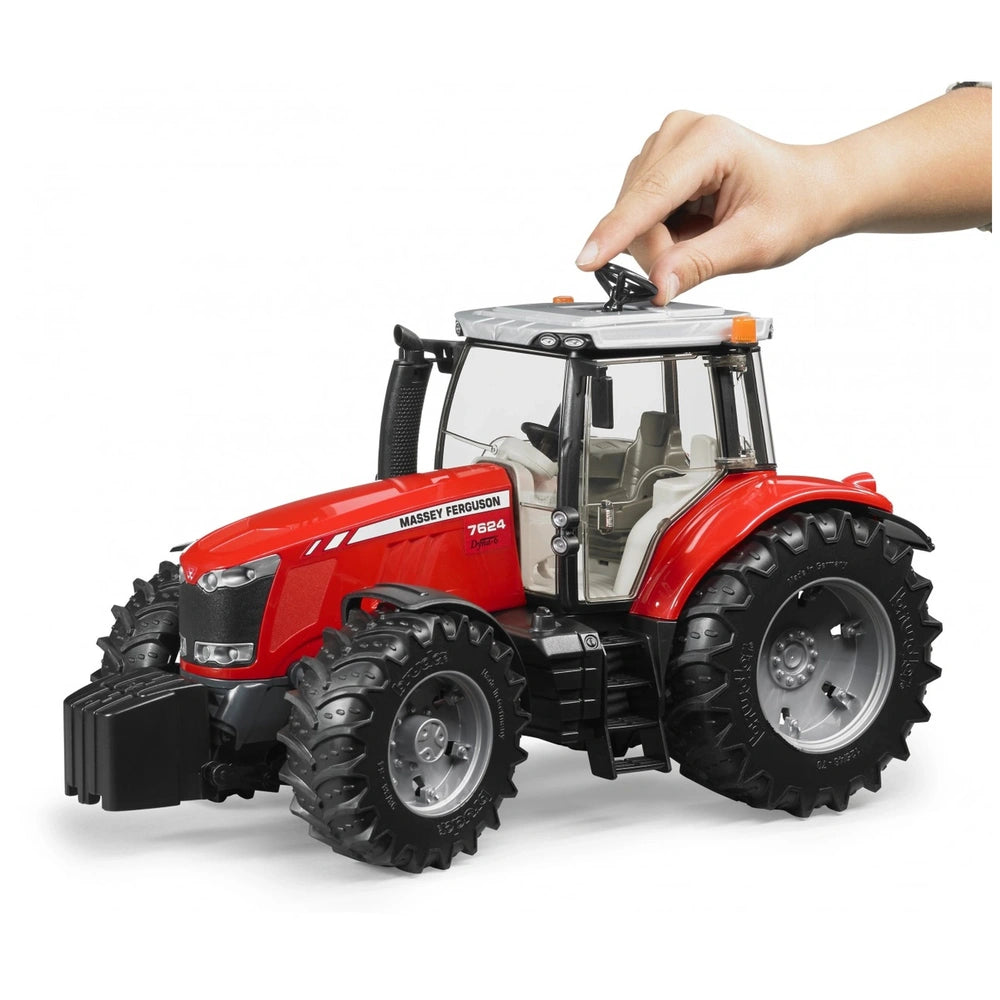Red Massey Ferguson 7624 toy tractor with large black tires and a hand operating the roof steering mechanism.