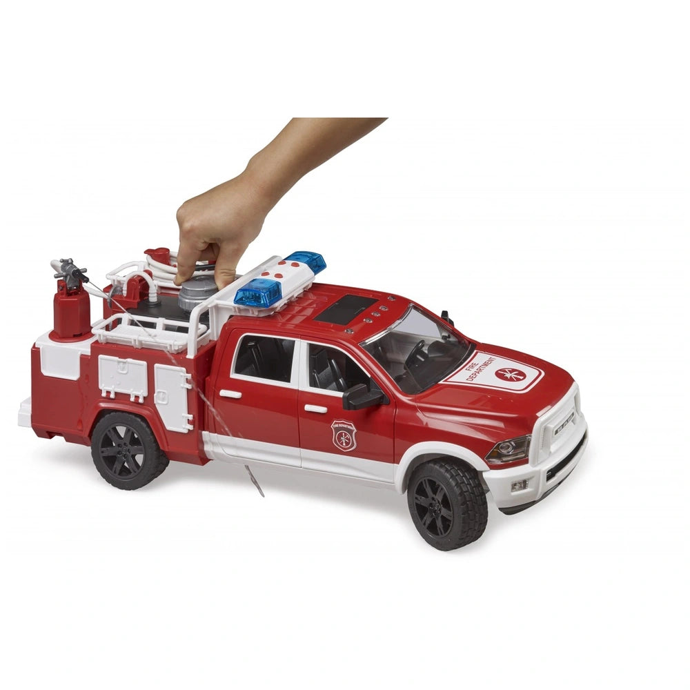 Red Bruder RAM 2500 toy fire truck with water cannon, hand operating tank, blue light on top, detailed cab.