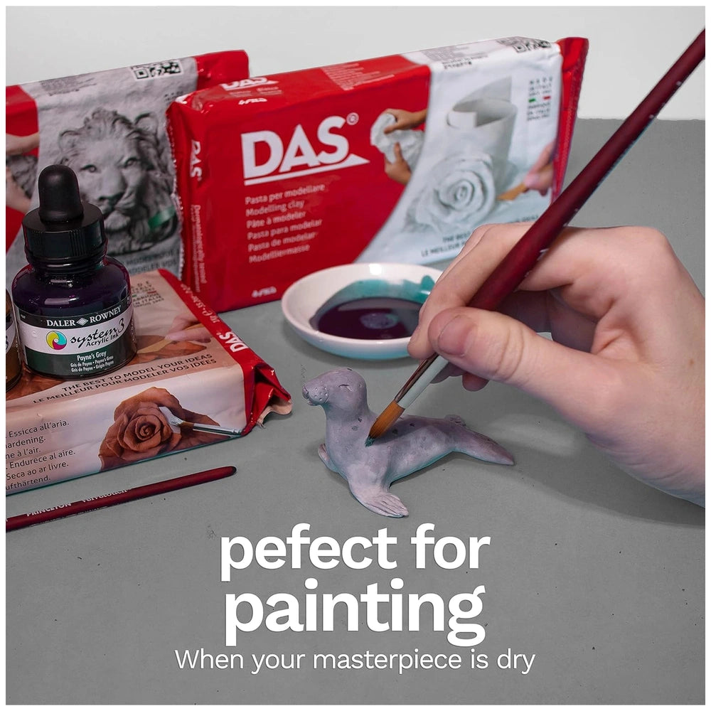 Das Modeling Clay - White 1 Kg displayed on a gray surface with various paint palettes and brushes in vibrant colors.