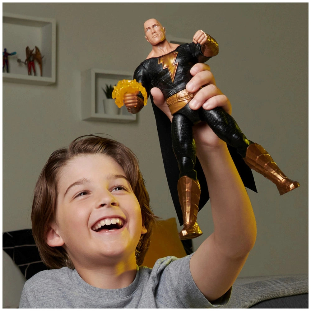 DC Comics Black Adam action figure in a young boy's hands, showcasing its glossy black and gold design indoors.