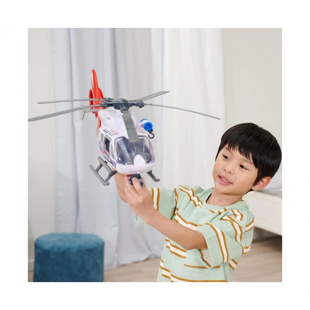 Giant helicopter play vehicle in a boy's hands, featuring white, red, and blue colors against a white wall and blue ottoman.