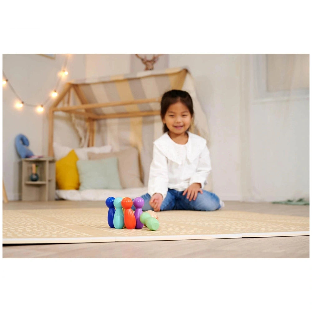 Eichhorn bowling game set displayed on a light floor, with a smiling girl in a white top and blue jeans engaging with colorfu