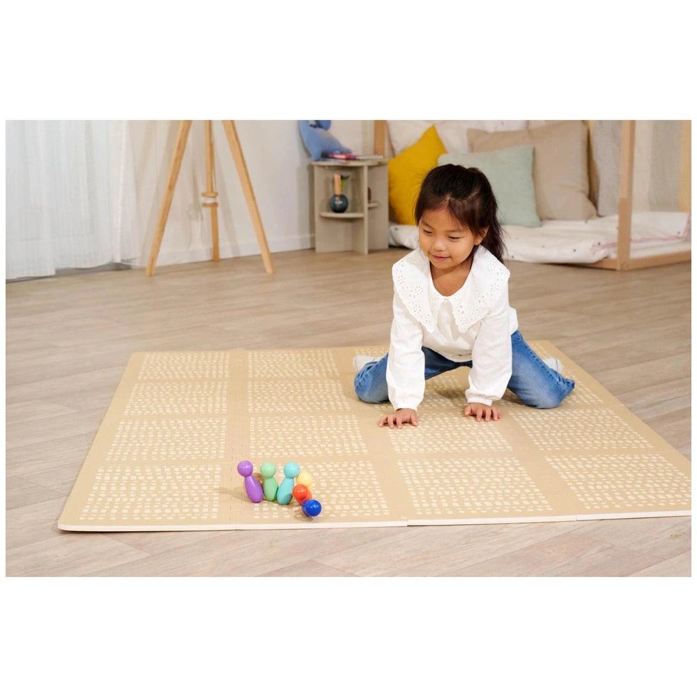 Eichhorn bowling game set up on a light-colored mat, with a young girl focused on playing in a cozy indoor setting.