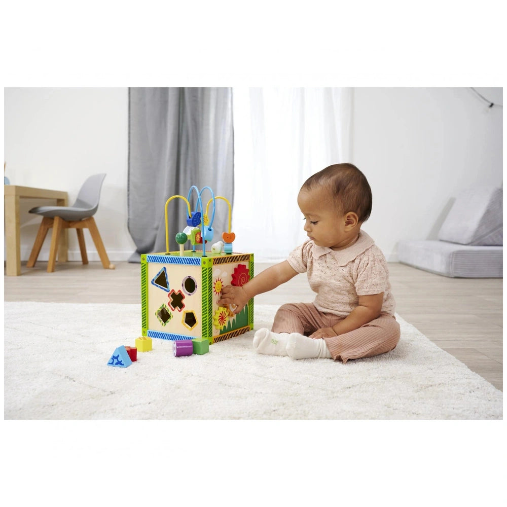 Eichhorn Color Little Play Center is a vibrant baby activity toy being explored by a young child on a white rug in a cozy roo