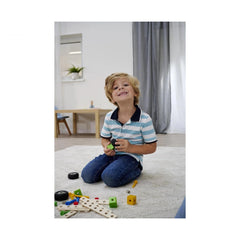Eichhorn Constructor Accessories construction set with a child in a striped shirt, surrounded by toys on a white carpeted flo