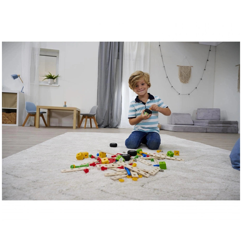 Eichhorn Constructor Accessories construction set with a young boy playing on a shaggy white rug beside a wooden table.