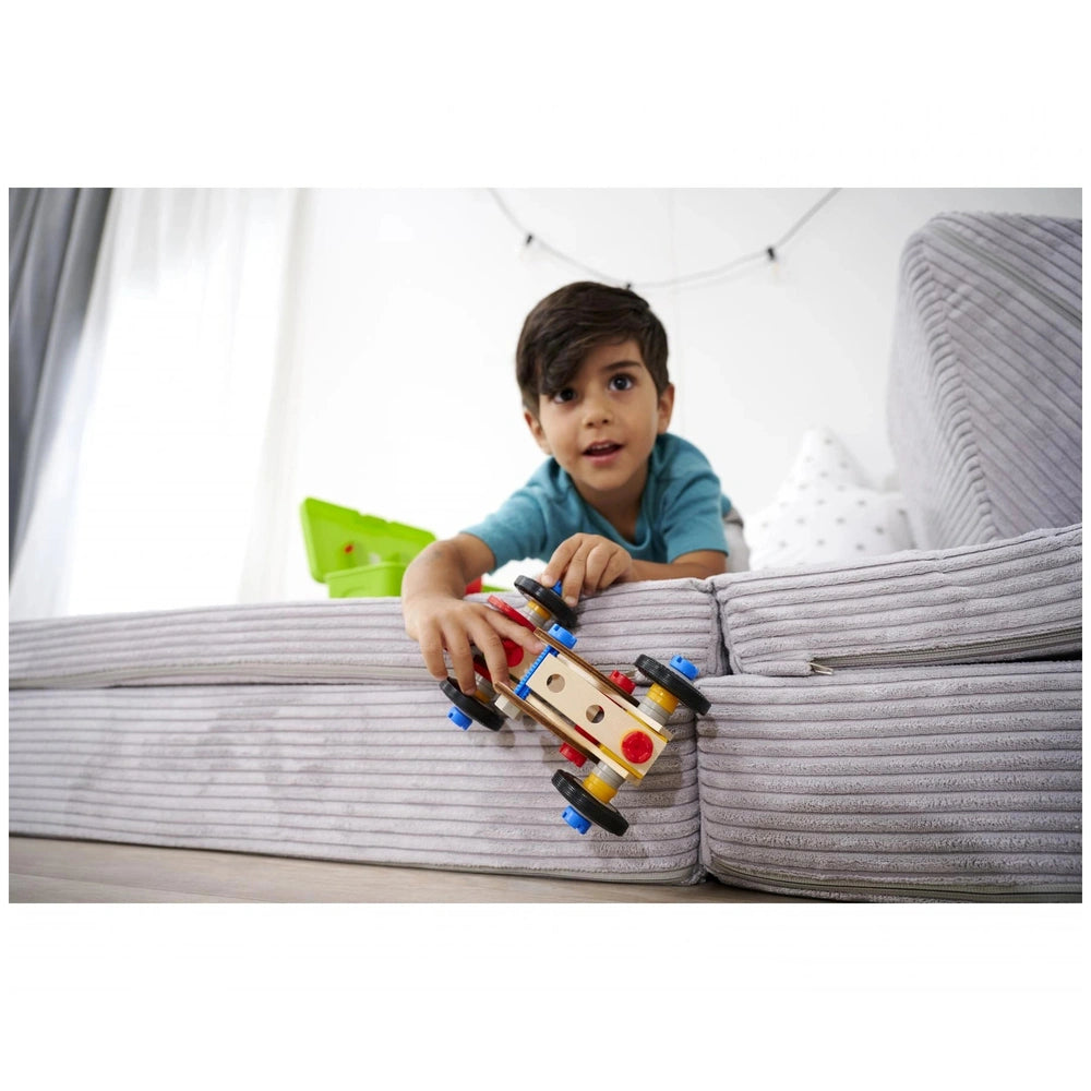 Eichhorn Constructor Racer Car set features a young boy playing with a red and yellow toy car on a gray couch.