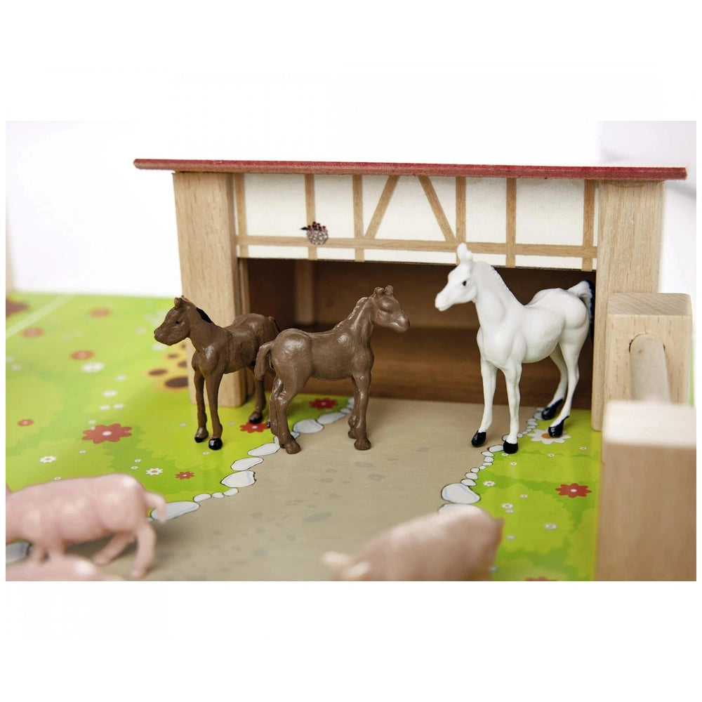 Eichhorn Little Farm Set featuring a wooden stable and three toy horses with a pink pig in a vibrant, detailed scene.