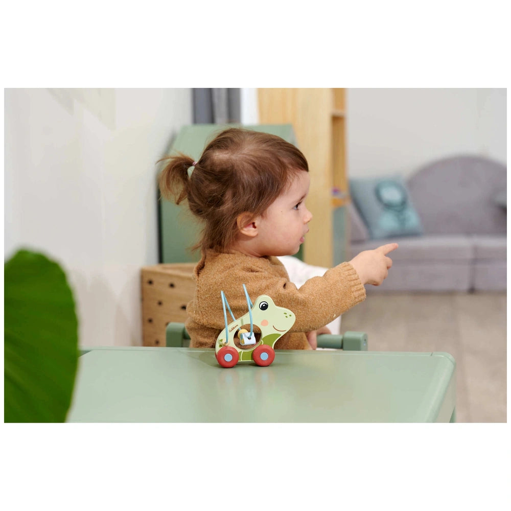 Eichhorn Push Frog baby activity toy with red wheels, child engaging with it in a cozy home environment.
