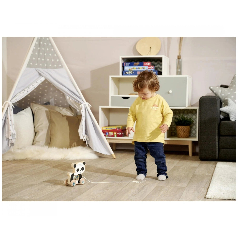 Eichhorn Wooden Pull Animal Panda toy being held by a child in a playful, brightly colored room with books and a teepee.