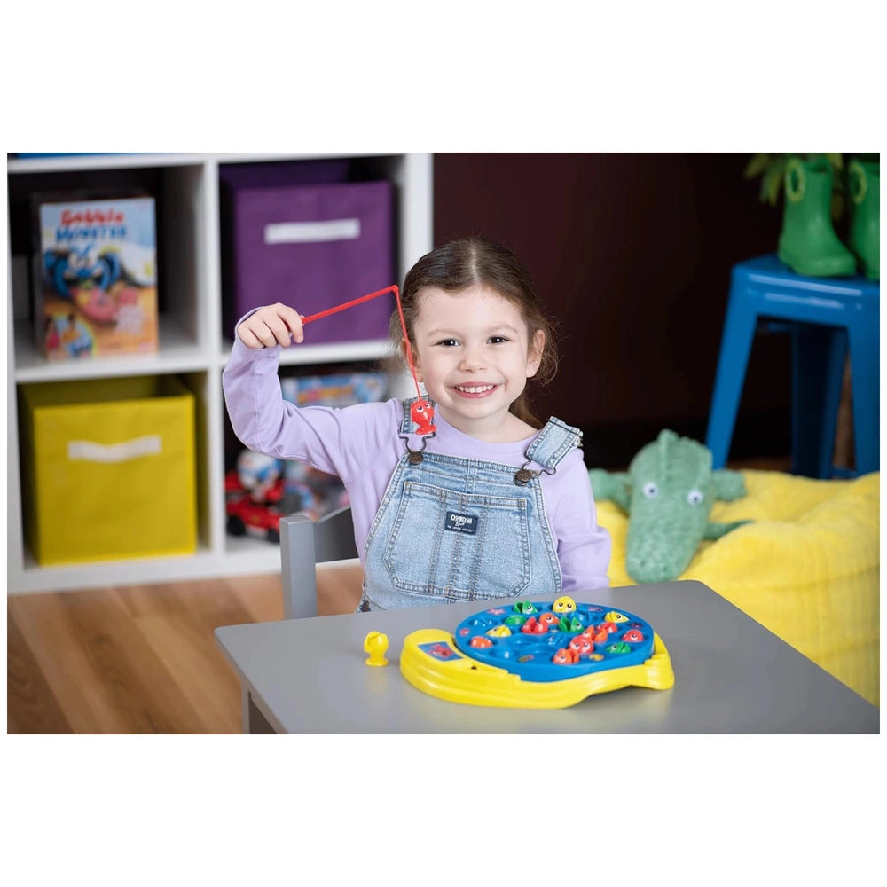 Goliath Let's Go Fishing Game features a young girl in purple shirt and blue overalls, playing with colorful toys on a gray t