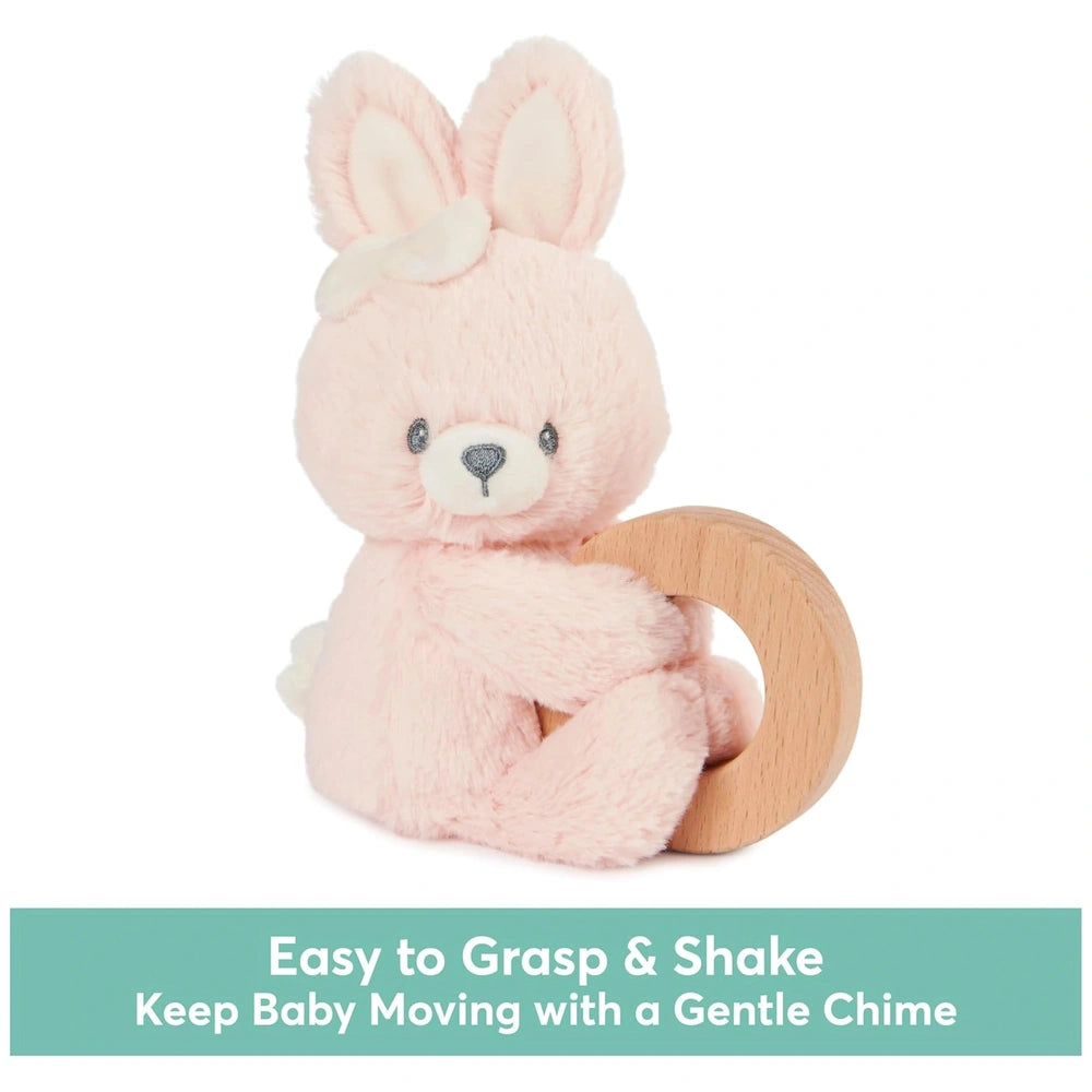 Pink bunny plush toy with white ears and bow, holding a smooth wooden ring against a white background.