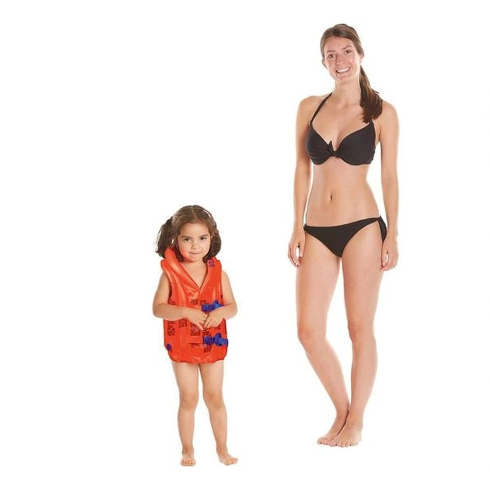 Happy People Bema inflatable life jacket in orange on a smiling child standing beside a woman in a black bikini at the beach.