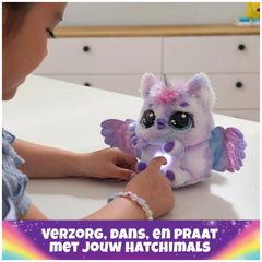 Hatchimals Alive Mystery Hatch Pufficorn plush toy in purple and blue held by a child, glowing softly on a white tabletop.