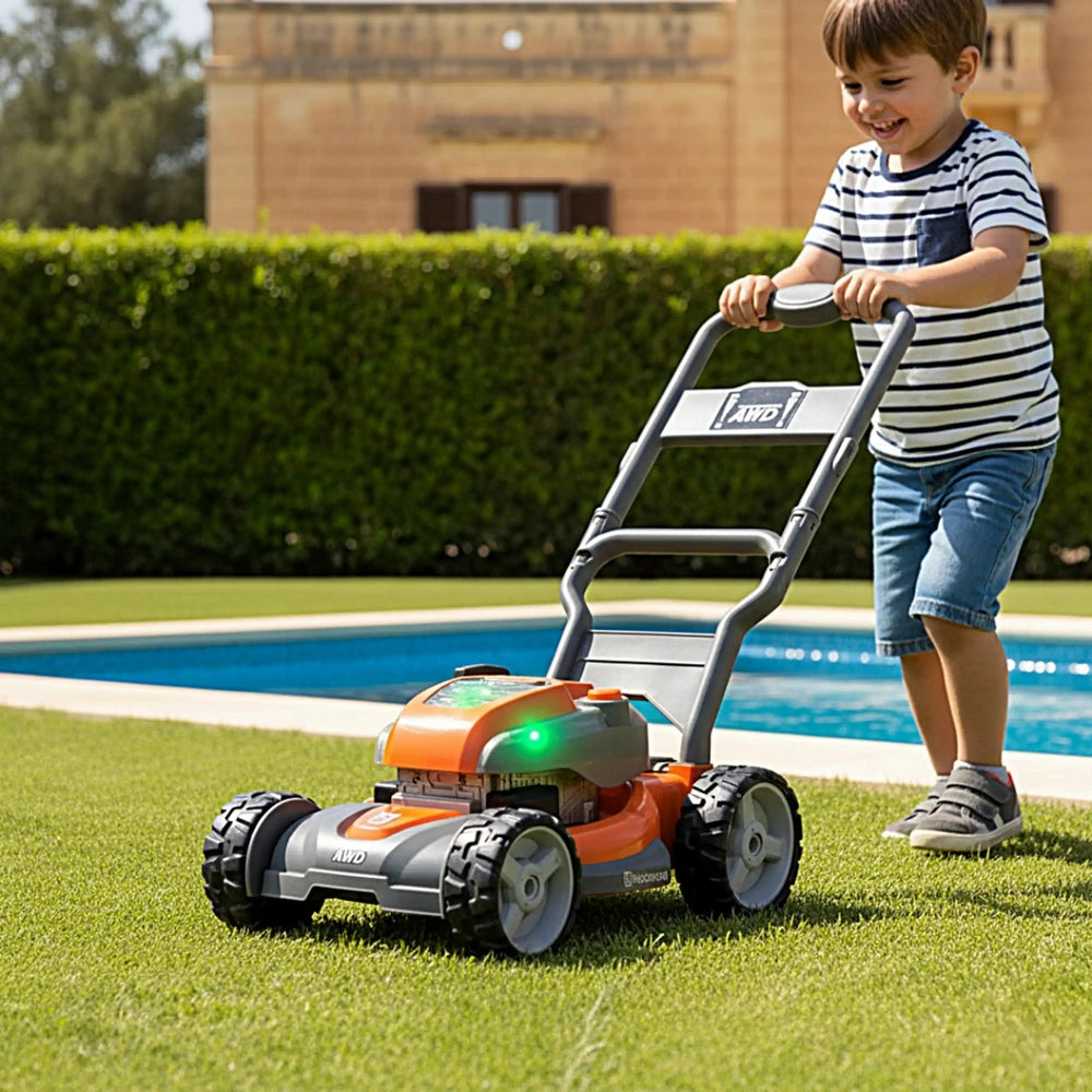 Boy in shorts stands by a blue swimming pool, pushing an orange plastic Husqvarna toy lawn mower on green grass.