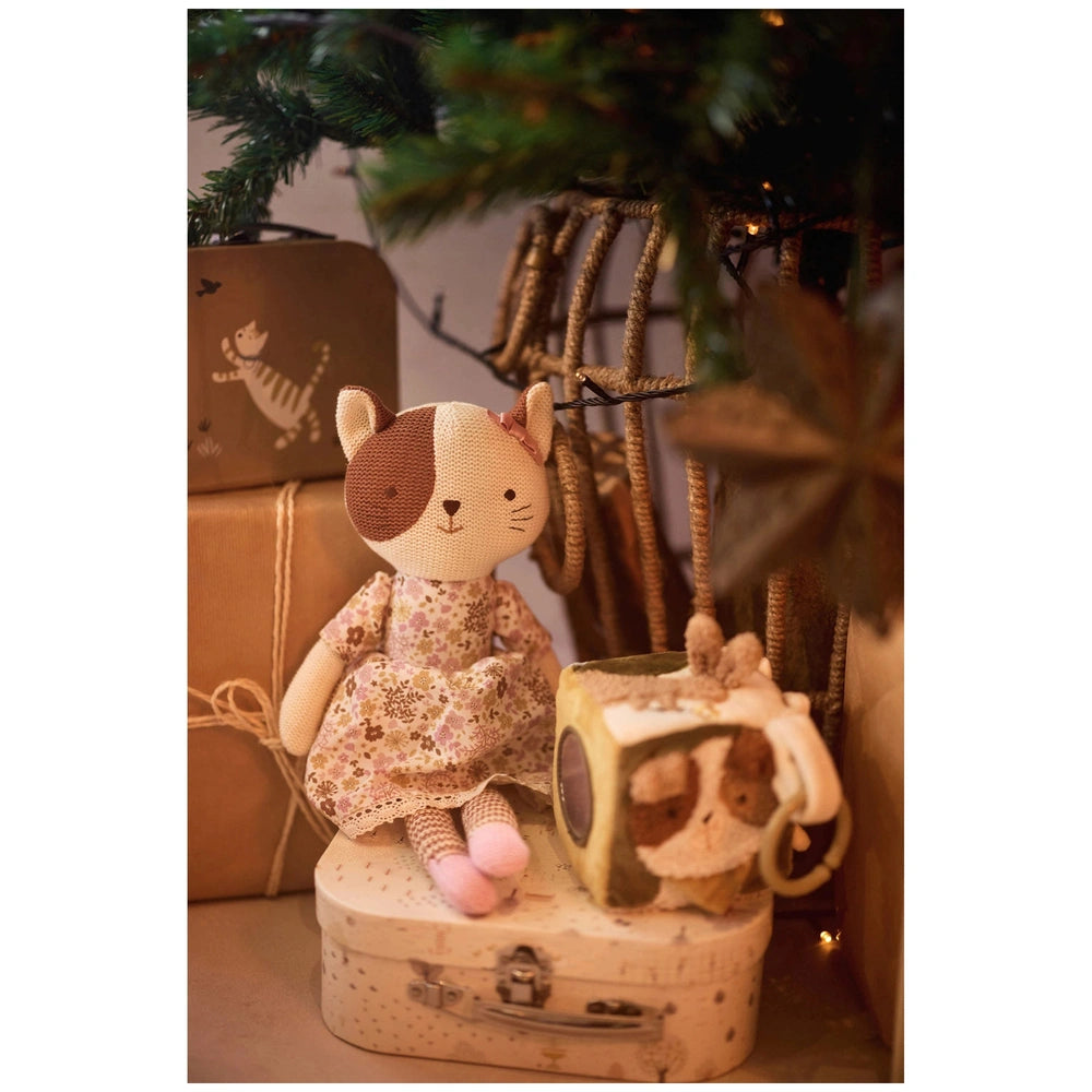 Jollein Activity Cube Tiny Park surrounded by white ceramic tea set on a floral patterned fabric, all on a brown cardboard bo