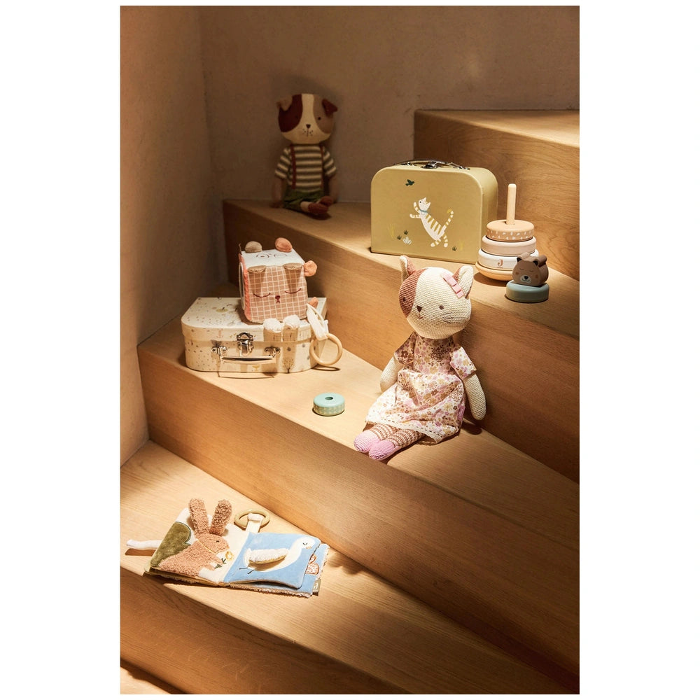 Jollein Soft Activity Book featuring colorful stuffed animals in floral and solid dresses arranged on wooden steps.