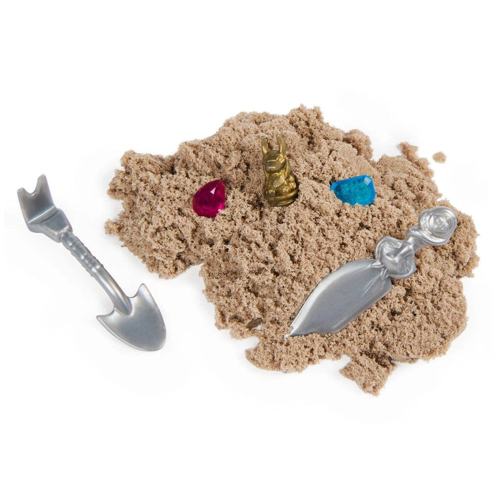Kinetic Sand Mummy Tomb features light brown sand with a silver spoon, fork, knife, and three colorful gemstones.
