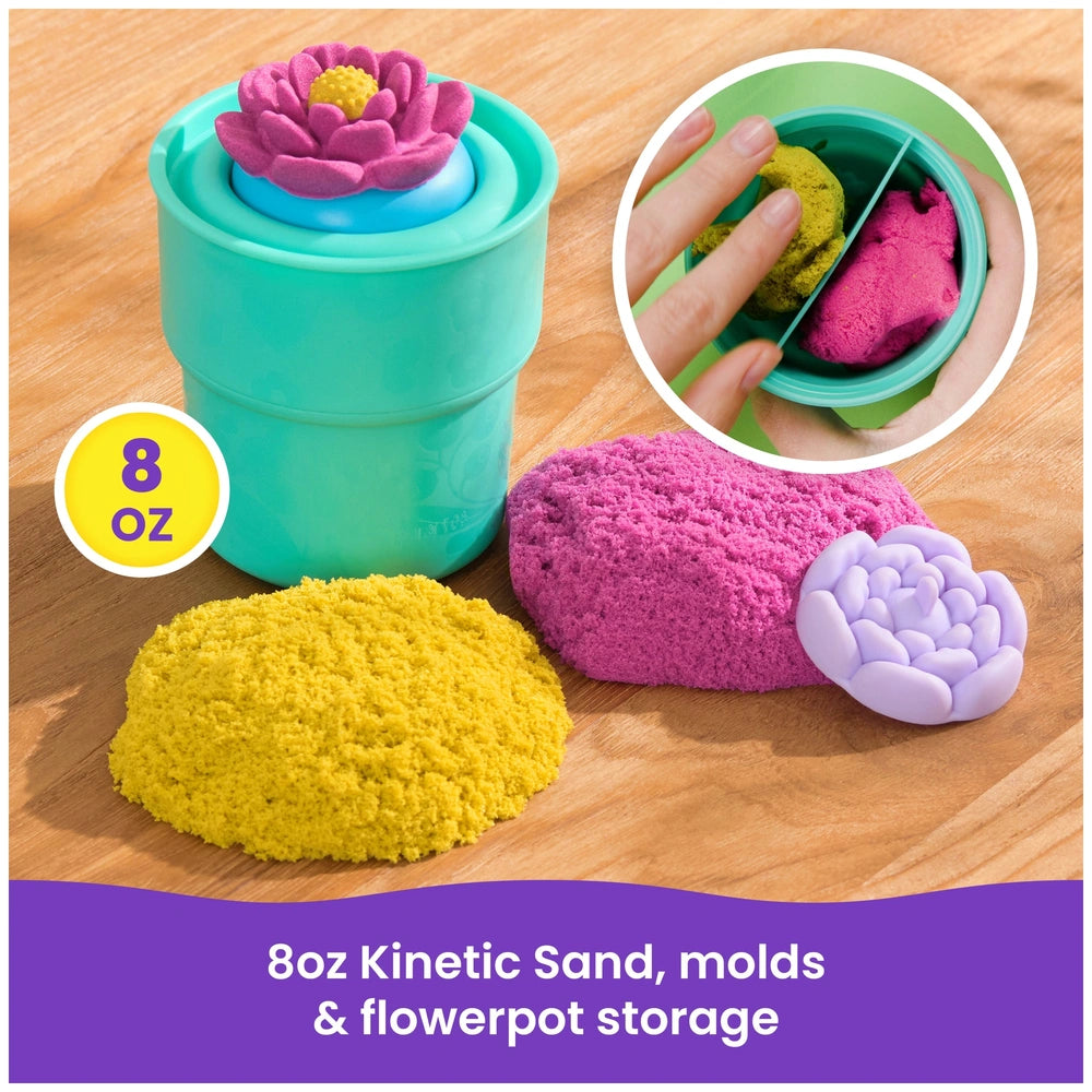Kinetic Sand in yellow with pink and purple molds, topped by a green flowerpot storage container on a wooden surface.