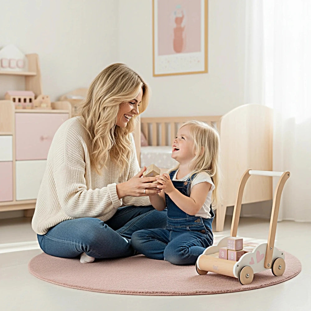 Label-Label educational baby walker surrounded by a woman and child on a pink rug with wooden furniture in the background.