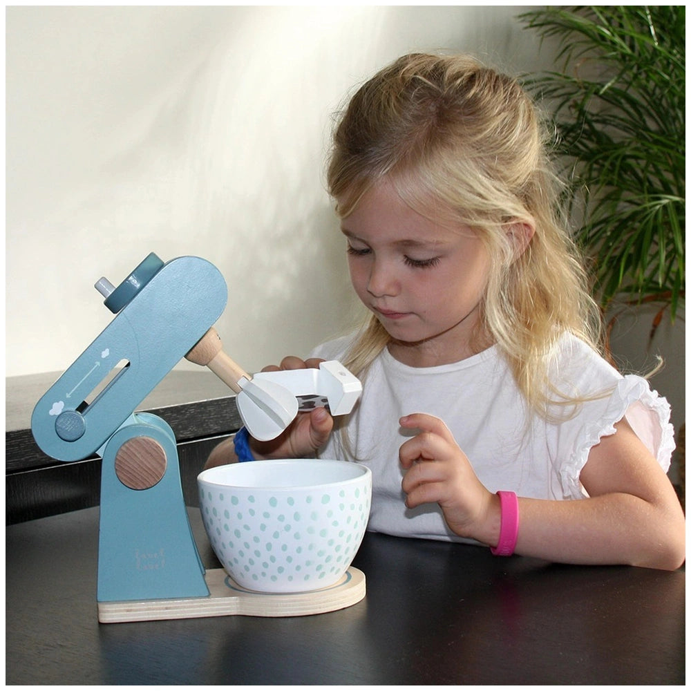 Label-Label Food Processor toy with blue and white colors, held by a blonde girl in a white top and pink wristband on a dark 
