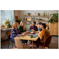 LEGO Art Keith Haring Dancing Figures displayed on a wooden table surrounded by five engaged individuals in a cozy setting.