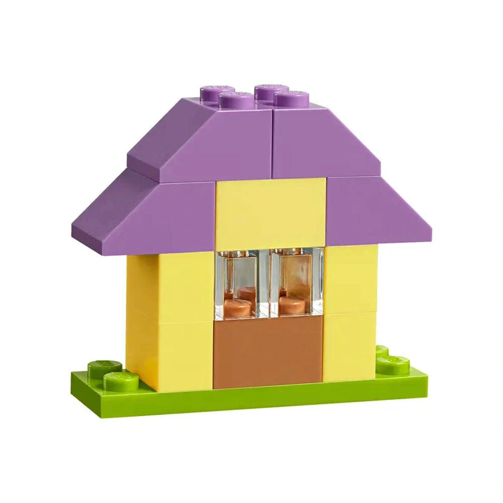 Colorful LEGO house with a purple roof, yellow walls, and brown door, set on a green base, showcasing imaginative design for creative play.