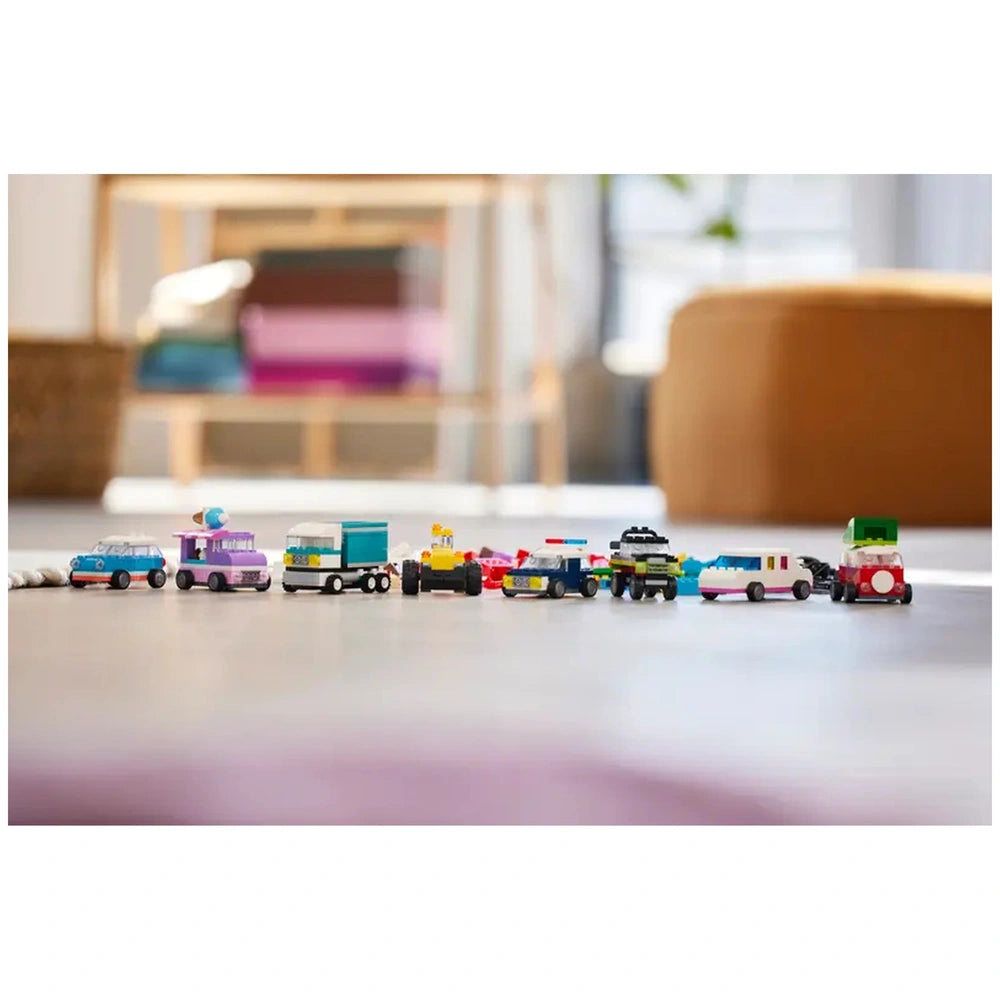 Colorful LEGO® vehicles lined up on a bright floor, featuring a police car, ice-cream truck, and various other unique designs, showcasing creativity and fun.