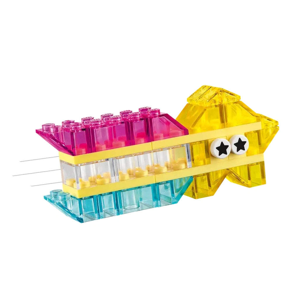 Colorful LEGO® construction set model shaped like a whimsical fish, featuring transparent pink, yellow, and blue bricks, with star-shaped eyes.