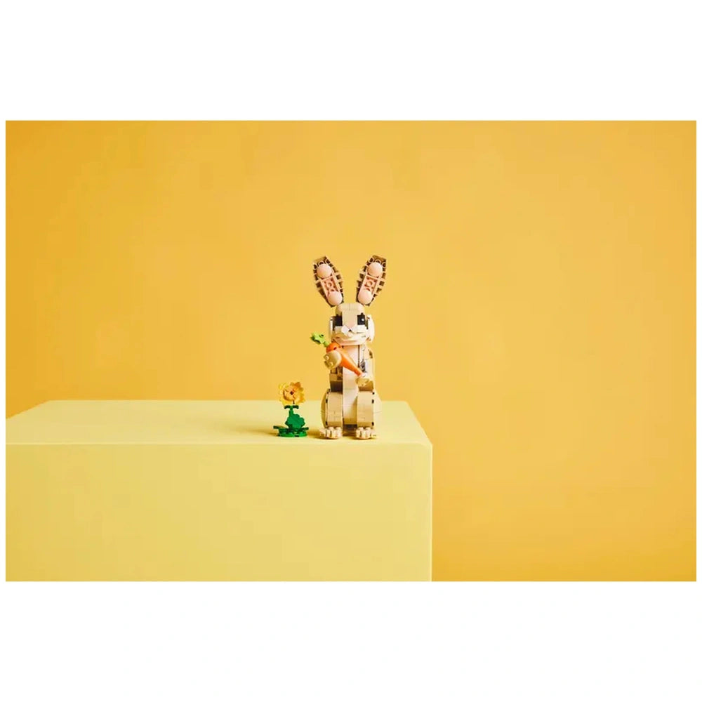 LEGO® Creator Cute Bunny set on a yellow pedestal, featuring a posable bunny holding a carrot beside a green flower.