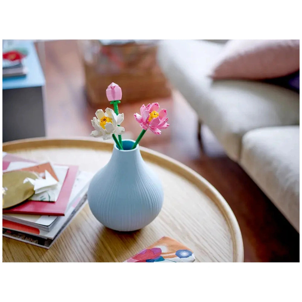 Colorful LEGO® Creator Lotus Flowers in a light blue vase, featuring pink and white blooms with green stems, placed on a wooden table.