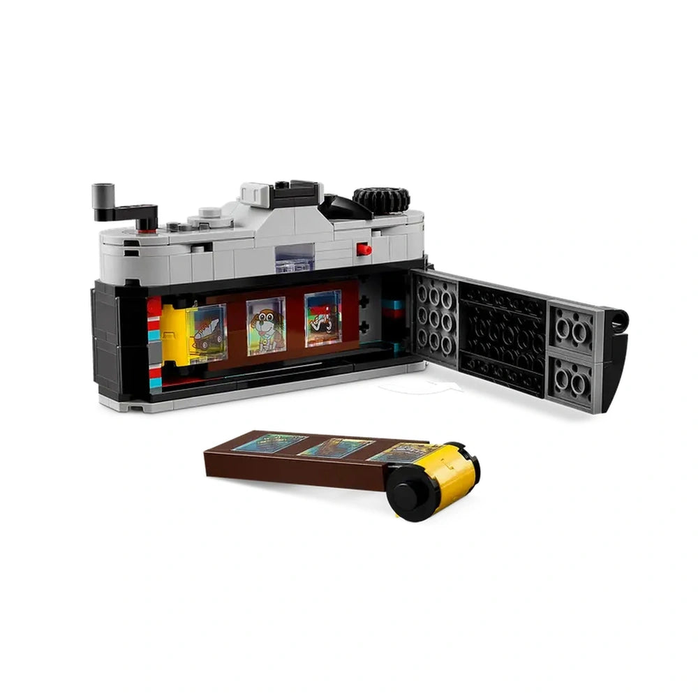 Retro camera construction set with a gray body, open back showcasing brick-built film and three colorful snapshots inside.