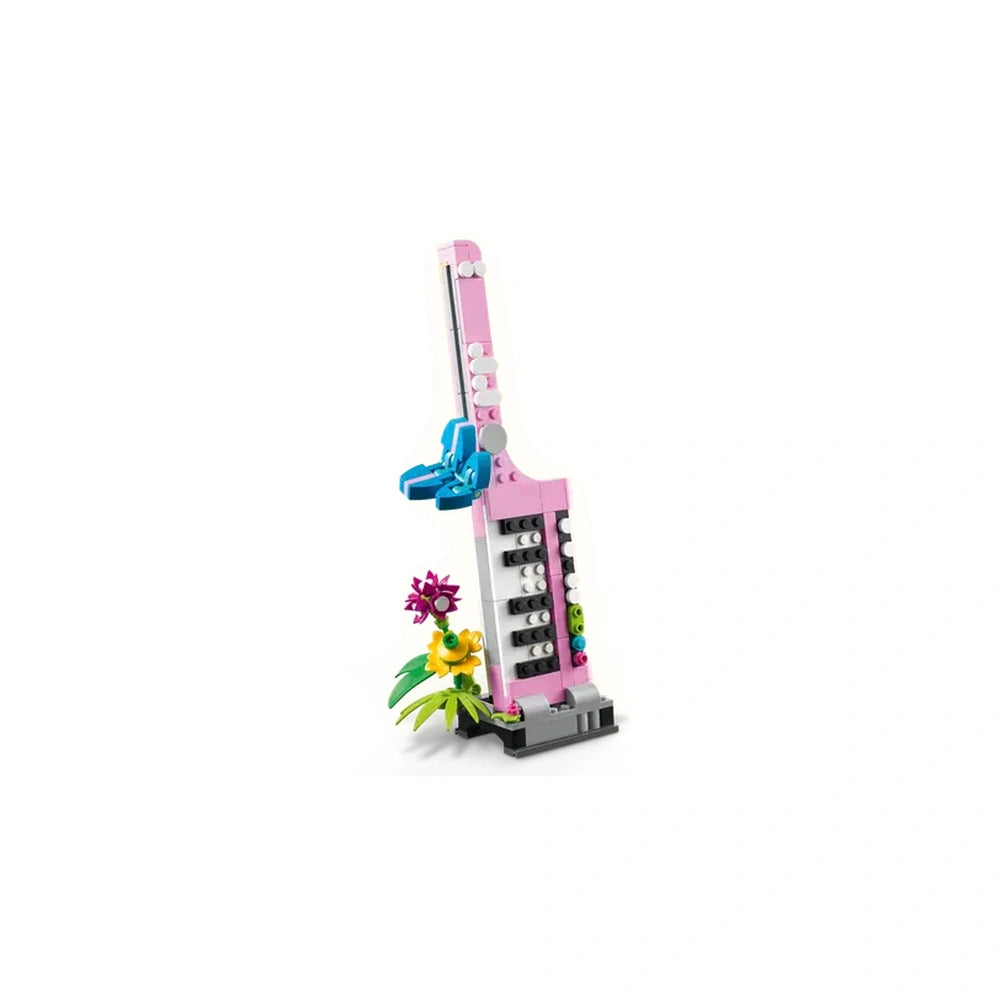 LEGO Creator 3in1 typewriter in pink featuring a moving keyboard, with vibrant brick-built flowers in yellow and purple at the base.