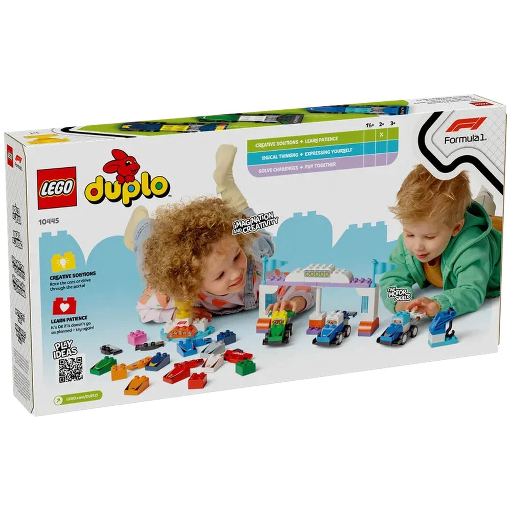 Two children play with a Lego Duplo F1® Team Race Cars set, building colorful race cars and a winner's podium on a blue surface.