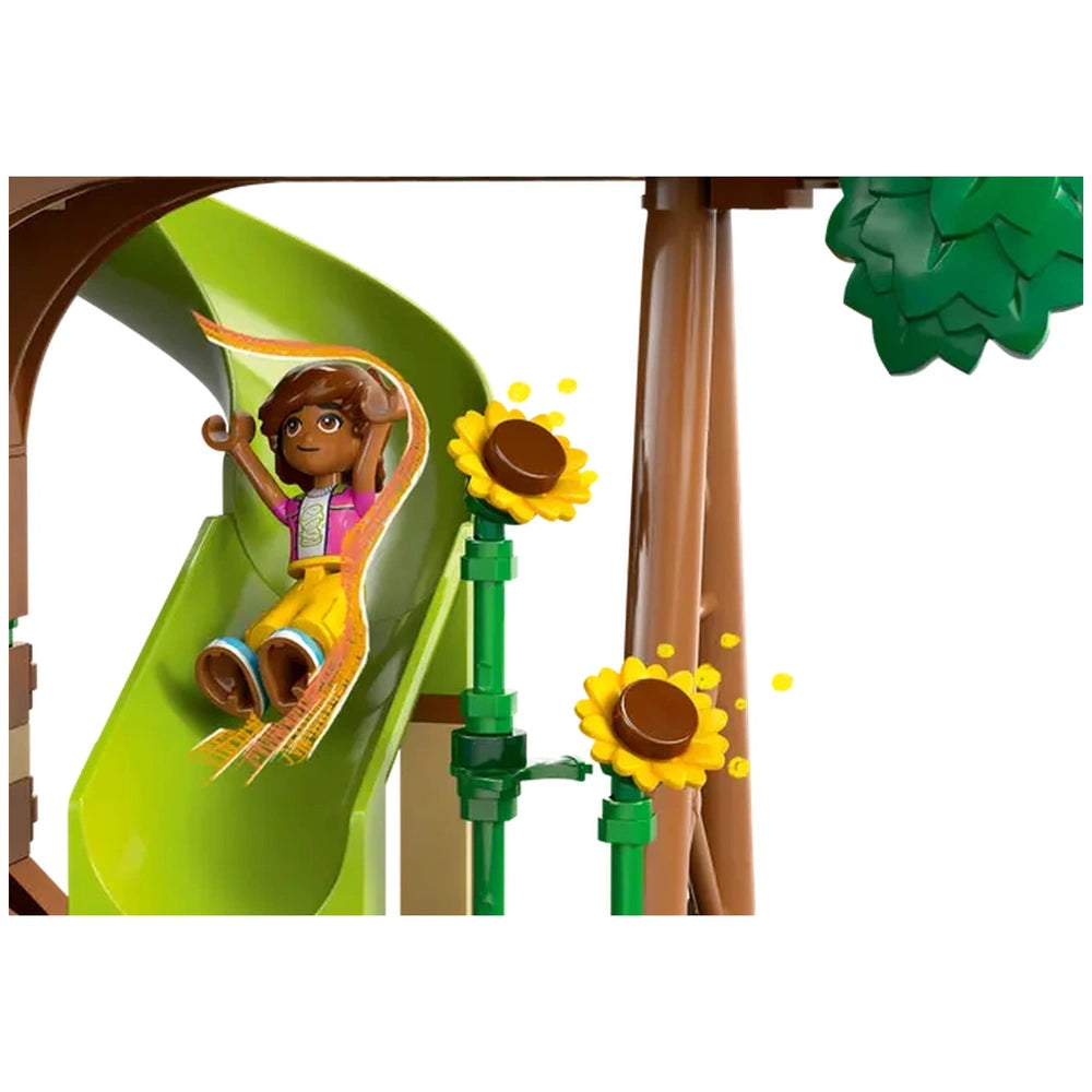 A LEGO Friends minidoll joyfully slides down a vibrant green slide, surrounded by cheerful yellow sunflowers and tree elements, full of fun and adventure.