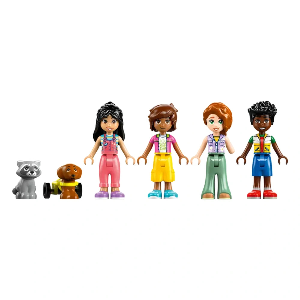 Four LEGO Friends minidolls stand side by side, each wearing colorful outfits, alongside a playful dog and a mischievous raccoon.