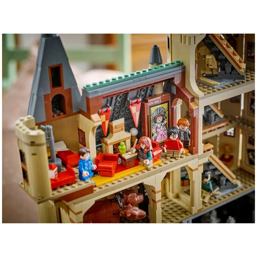 Detailed view of the LEGO Harry Potter Hogwarts Castle interior, featuring minifigures in a cozy living area with colorful furniture, decorative portraits, and a staircase.