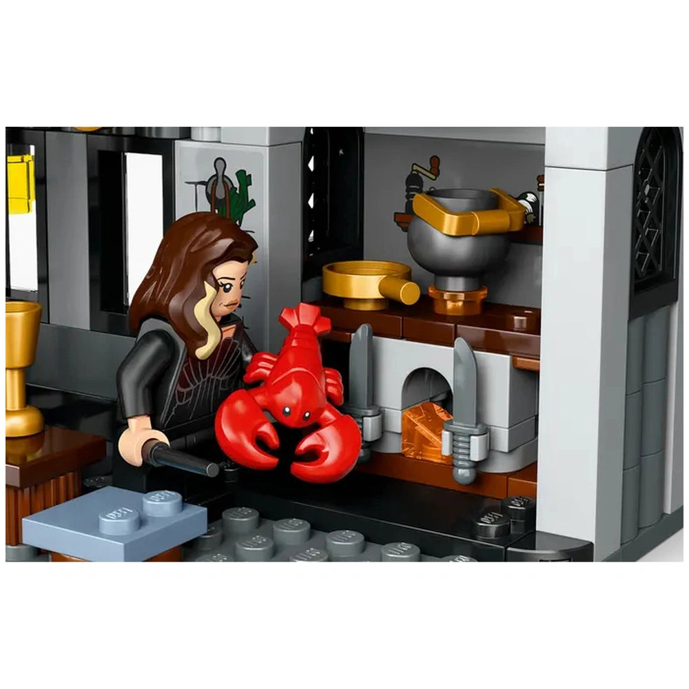 A LEGO® Harry Potter™ figure holds a red lobster in a detailed Malfoy Manor kitchen, featuring a fireplace, cauldron, and golden utensils.