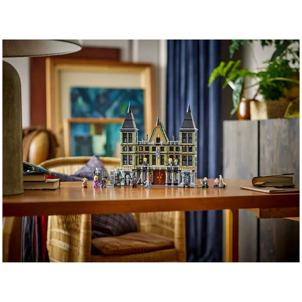 LEGO® Harry Potter™ Malfoy Manor construction set displayed on a wooden table, featuring detailed architectural elements and multiple minifigures.