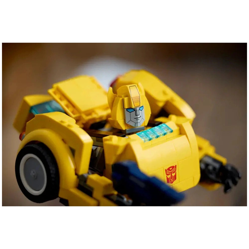 Detailed yellow Bumblebee model featuring articulated joints, blue eyes, and Autobot logo, set against a blurred background.